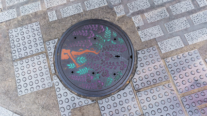 Fototapeta na wymiar Tree figure on manhole cover at the street in Kurashiki, Japan