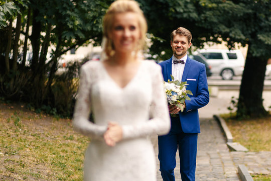 Happy smiling groom walks with nice wedding bouquet to bride