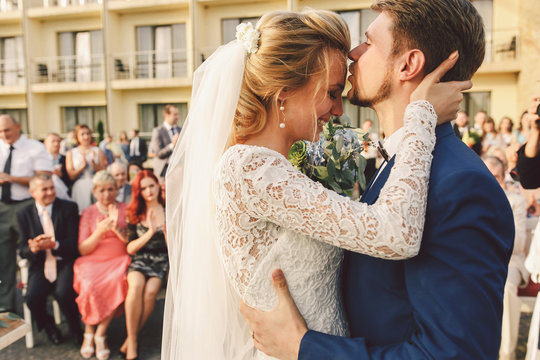 Bearded groom kisses bride's forehead while she cries