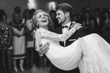 Groom admires happy bride laughing in his arms