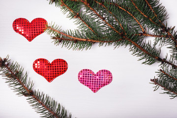 Wooden white background with a branch of pine and three hearts.