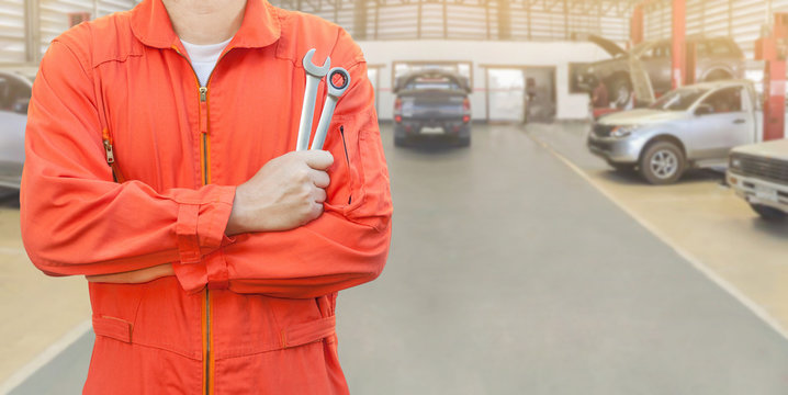 Mechanic holding wrench in car garage, Mechanic and tools concept.