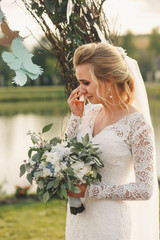 Gorgeous bride cries standing before arch made of woven branches