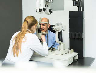 female ophthalmologist and mature patient checking eyesight in c