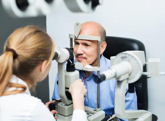 Fototapeta na wymiar Female optician doing eye examination with aid of slit lamp