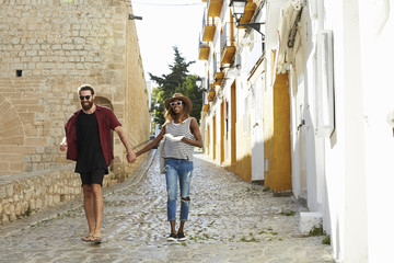 Obraz na płótnie Canvas Couple on holiday walking in Ibiza streets with a guidebook