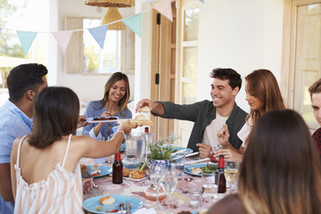 Friends serving each other at a patio dinner party, close up