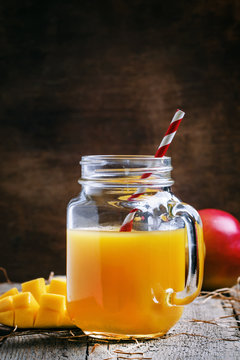 Mango juice with straw on old wooden background, selective focus