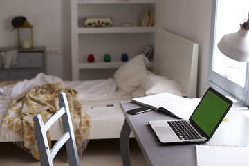 Teenager’s bedroom, with laptop on desk and unmade bed