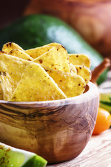 Corn nachos with salt in wooden bowl, old wooden background, sel