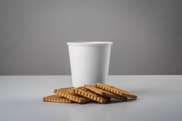 Some white cup with biscuit on gray table