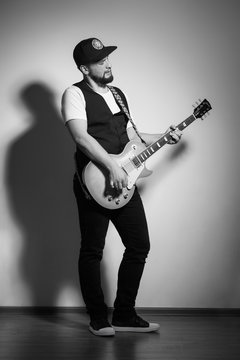 handsome bearded musician playing guitar over gray background
