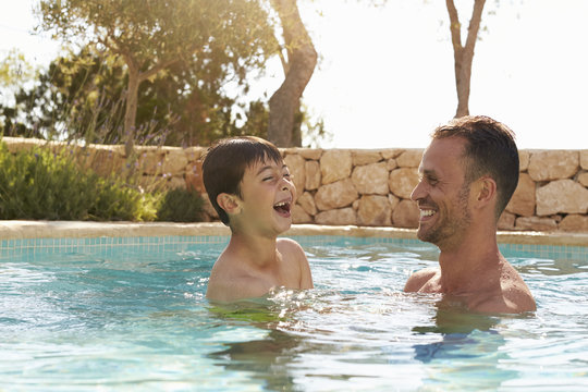 Father And Son On Vacation Having Fun In Outdoor Pool