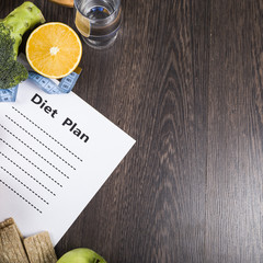 Food and sheet of paper with a diet plan on a dark wooden table.