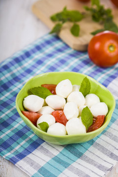 Mozzarella in a green plate on a wooden table. Mozzarella balls