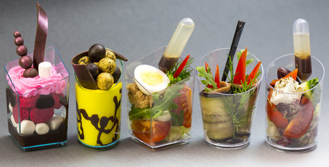 Mini desserts and meat canapes vegetable snacks in plastic cups canapes