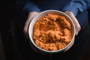 Hummus in the  bowl in the woman's hands