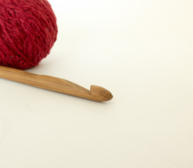 Wooden hook with a ball of wool on white