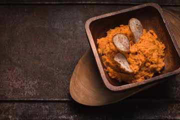 Hummus in the wooden bowl on the old metal background horizontal
