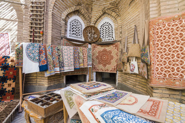 The wide range of the hand made carpets, traditional knotted Uzbek silk rugs, embroidered tablecloths and bed linen in the small bazaar, Khiva, Uzbekistan, Central Asia