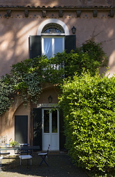 Facade of an Italian villa overgrown with climbing plant.