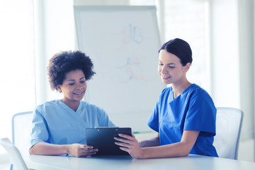 happy doctors with tablet pc meeting at hospital