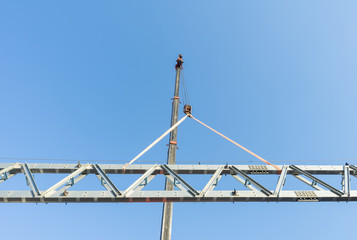 Construction site crane is used to placing steel roof frame