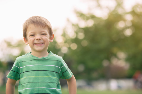 happy smiling blond caucasian kid outdoor portrait at park
