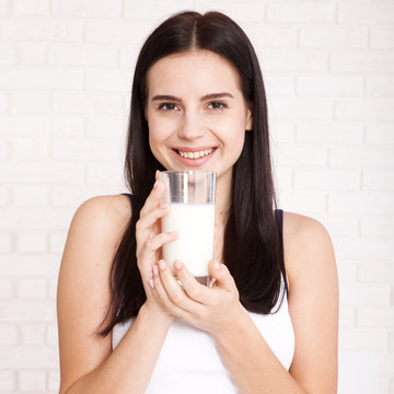 Young girl drinking a glass of milk in the morning for breakfast. Concept Healthy Eating. Beautiful face of woman close, square