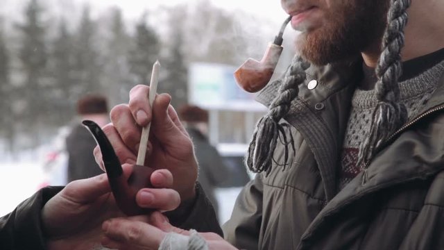 two man with a beard in the winter get a light pipe