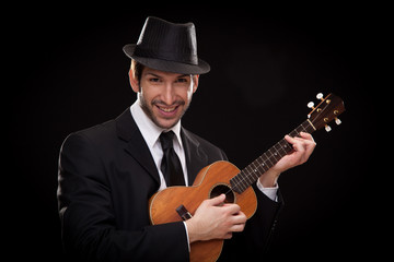 Obraz premium elegant happy man singer musician playing ukulele guitar isolated on black