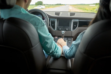 happy couple driving in car and holding hands