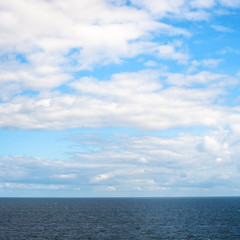 Fototapeta na wymiar low white clouds in blue sky over Baltic Sea