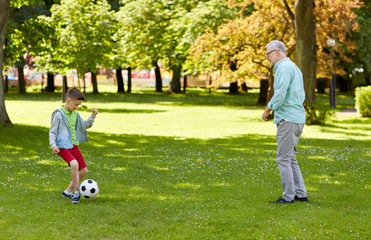 Obraz premium old man and boy playing football at summer park