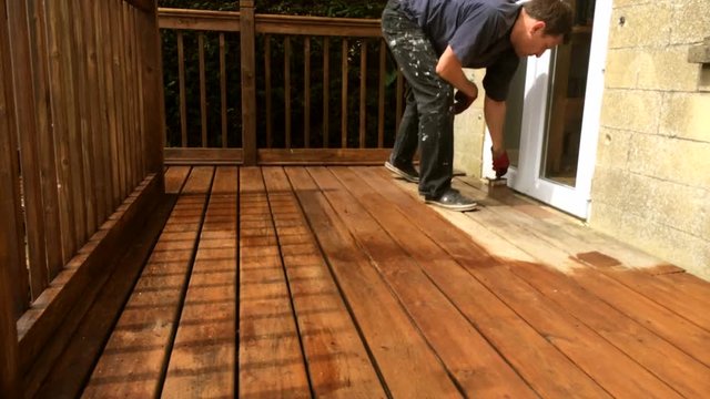Timelapse of a deck balcony being oiled with a stain and protector by hand by brush. 