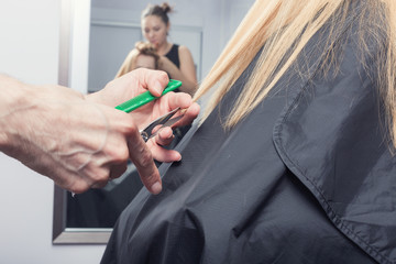 A hairdresser making a haircut for blonde female