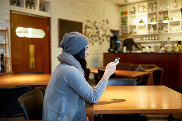 young woman with smartphone at cafe