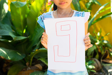 number concept,girl holding number nine on white paper