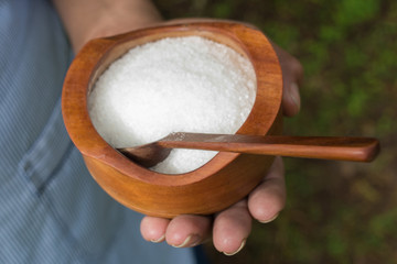 close up of holding hands with wooden bowl of salt