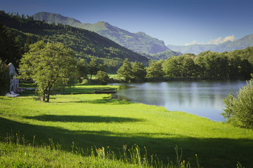 lake in mountain with green field and blue sky