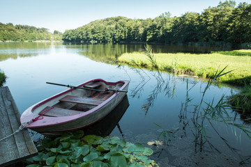 small boat in lake in mountain with green field and blue sky