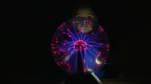 Little boy touching his hands and sees a plasma ball. Night Light lamp Tesla 