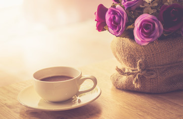 Happy weekend concept. White cup of coffee on wooden floor with purple flower in pot vintage color tone.