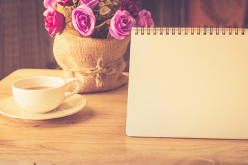Happy weekend concept. White cup of coffee on wooden floor with purple flower in pot vintage color tone.