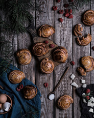 Fototapeta premium Buns with white chocolate and raspberries on a wooden table with pieces of chocolate, berries and pine branches