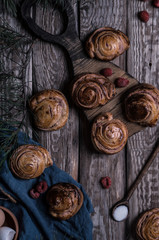 Buns with white chocolate and raspberries on a wooden table with pieces of chocolate, berries and pine branches