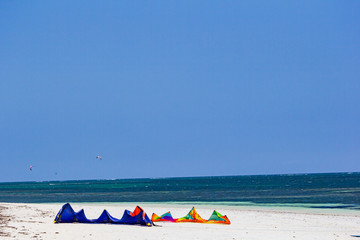 Two kitesurf parachute lying on the white beach