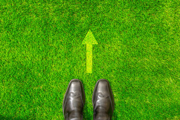 black shoes standing on grass wIth arrow sIgn, decision makIng concept