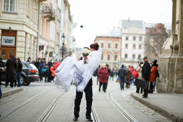 Groom carrying on hands beautiful bride