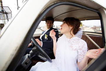 Bride and groom inside a classic car.